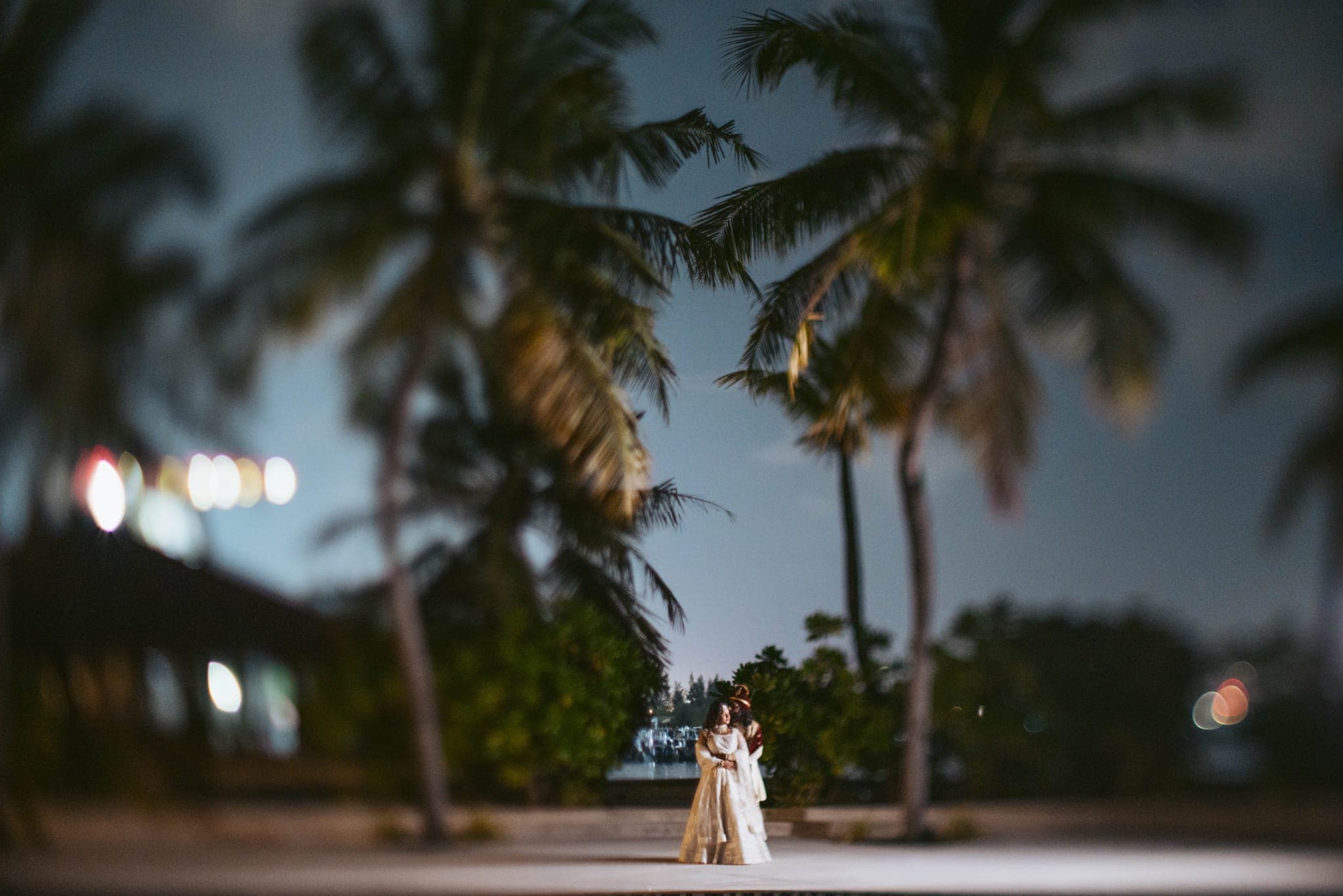 Couple embracing at night beneath silhouetted palm trees