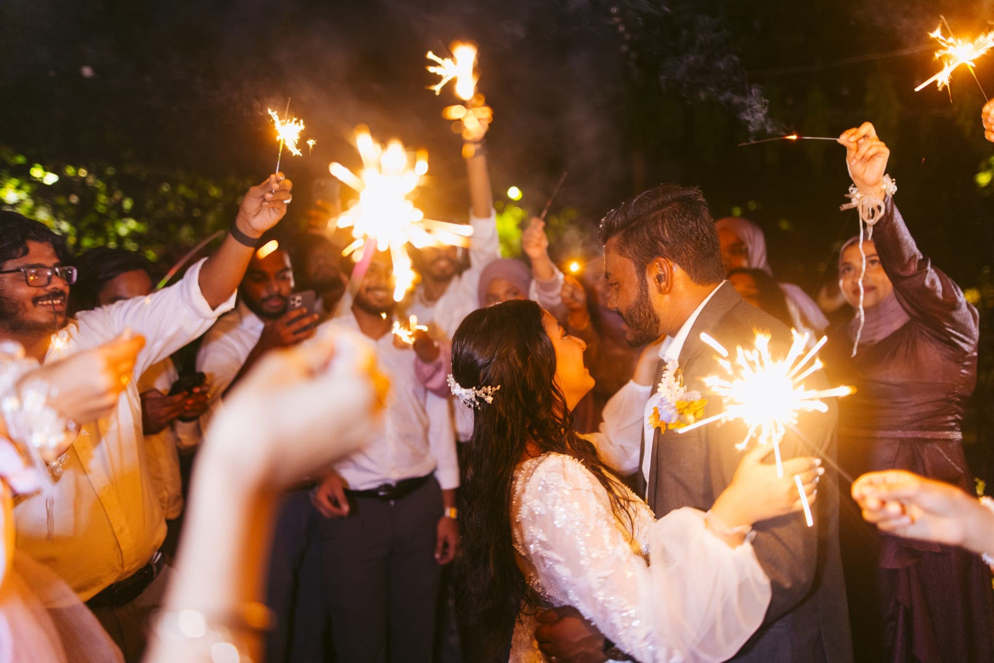 Wedding couple kissing amid guests waving sparklers