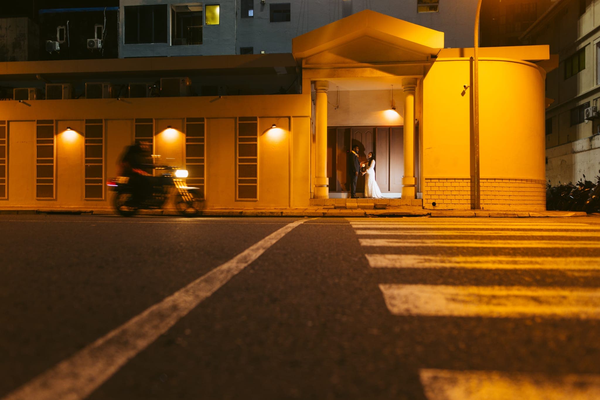 Motorbike passing illuminated yellow building at night
