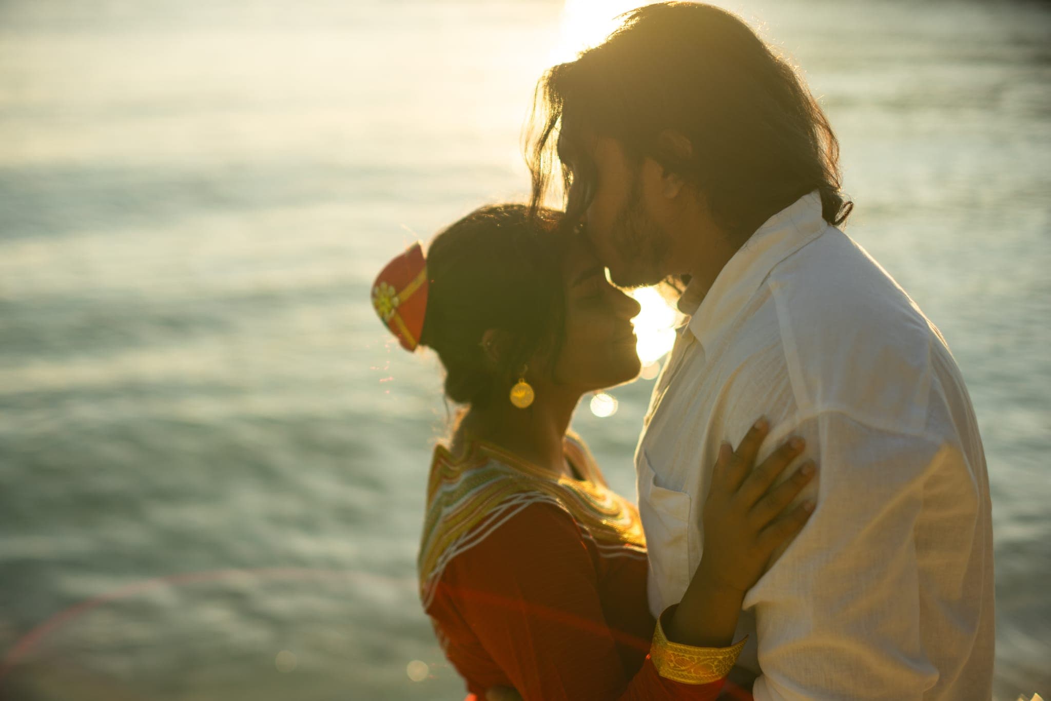 Couple embracing by water at golden hour sunset
