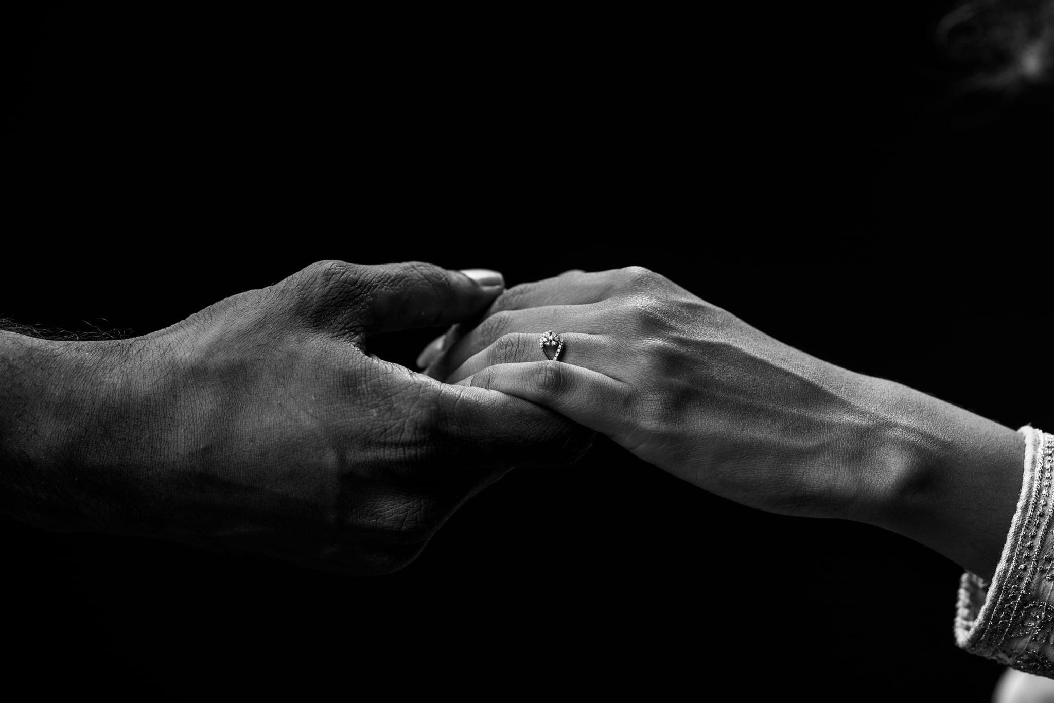 Close-up of couple's hands with wedding ring, black and white