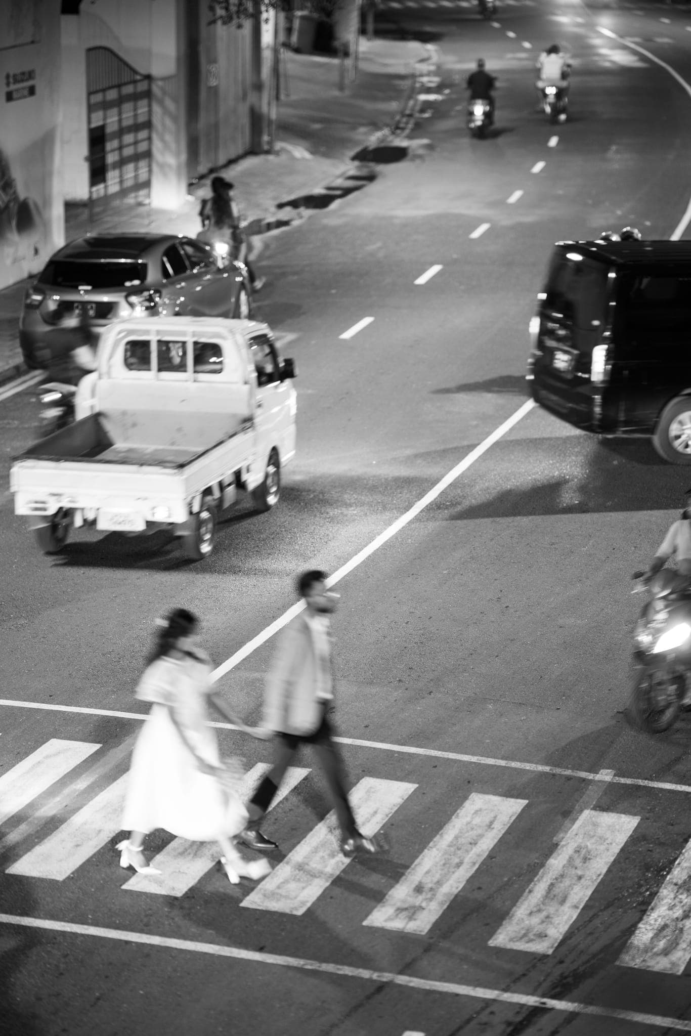 Bride and groom crossing city crosswalk at night