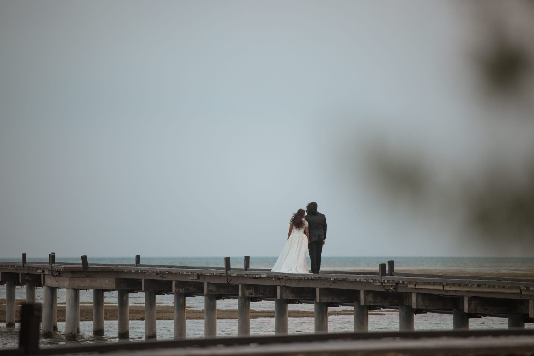 Couple silhouetted embracing on jetty over misty sea