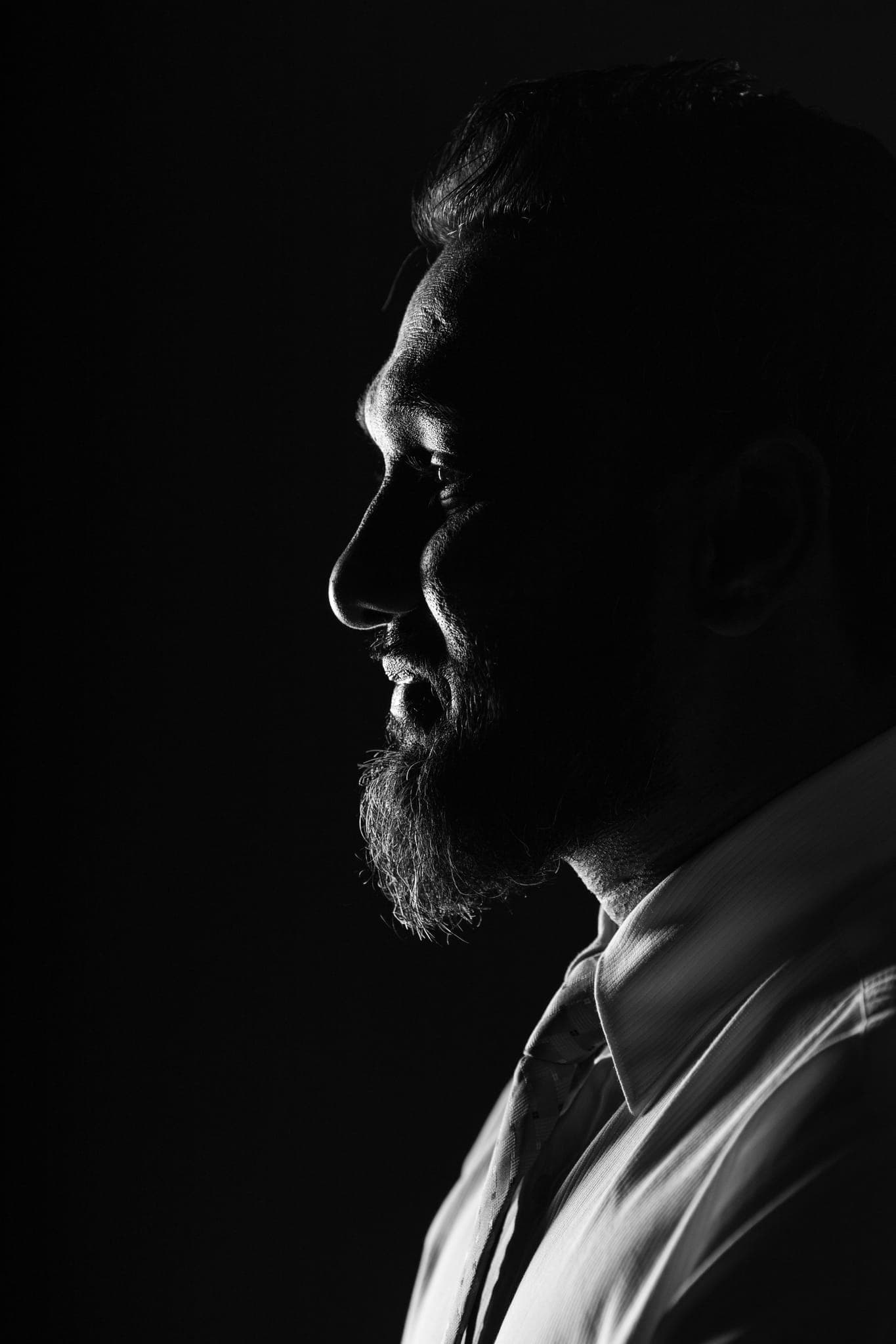 Bearded man's profile silhouetted against black background