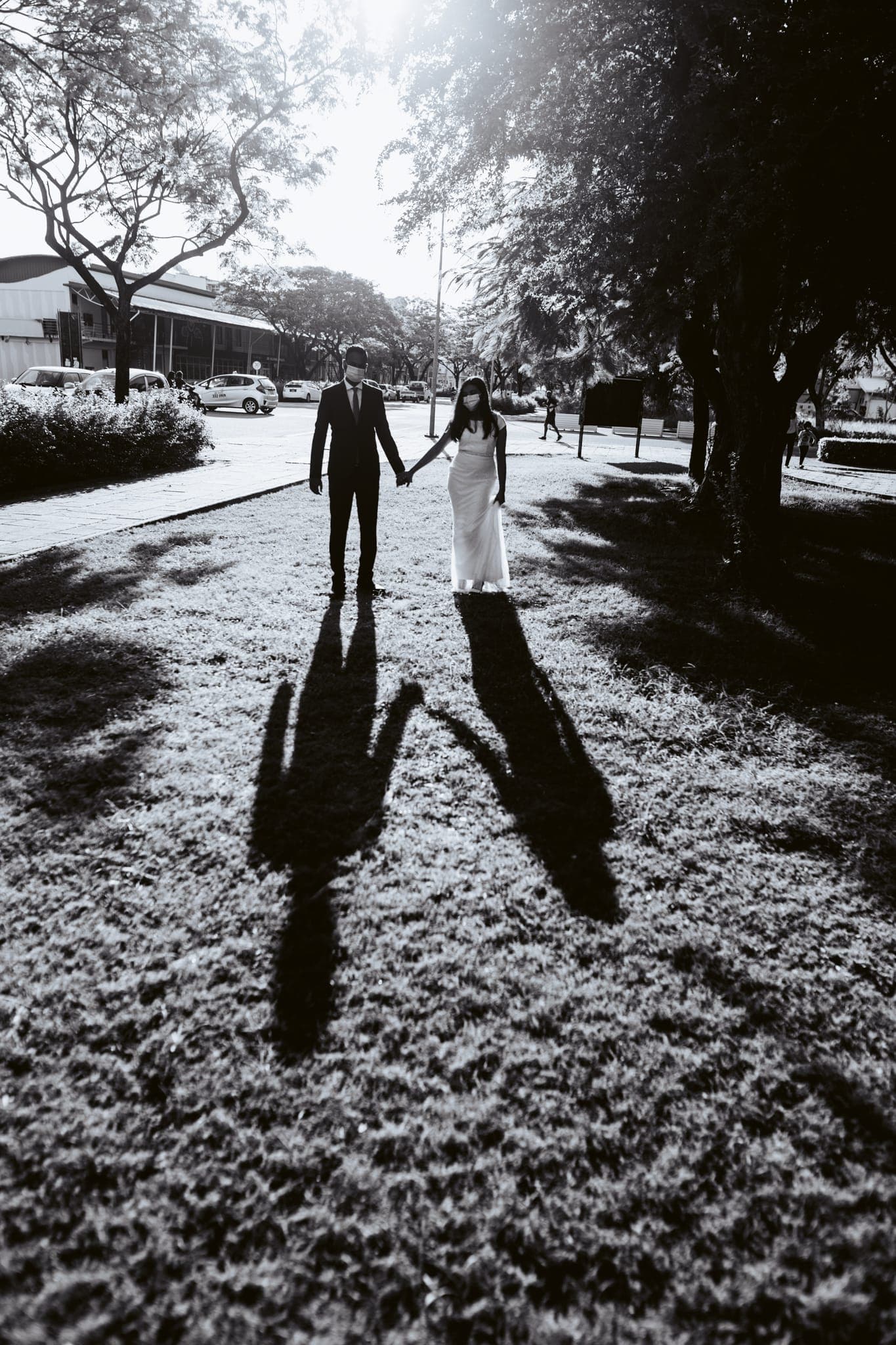 Couple holding hands casting long shadows on grass