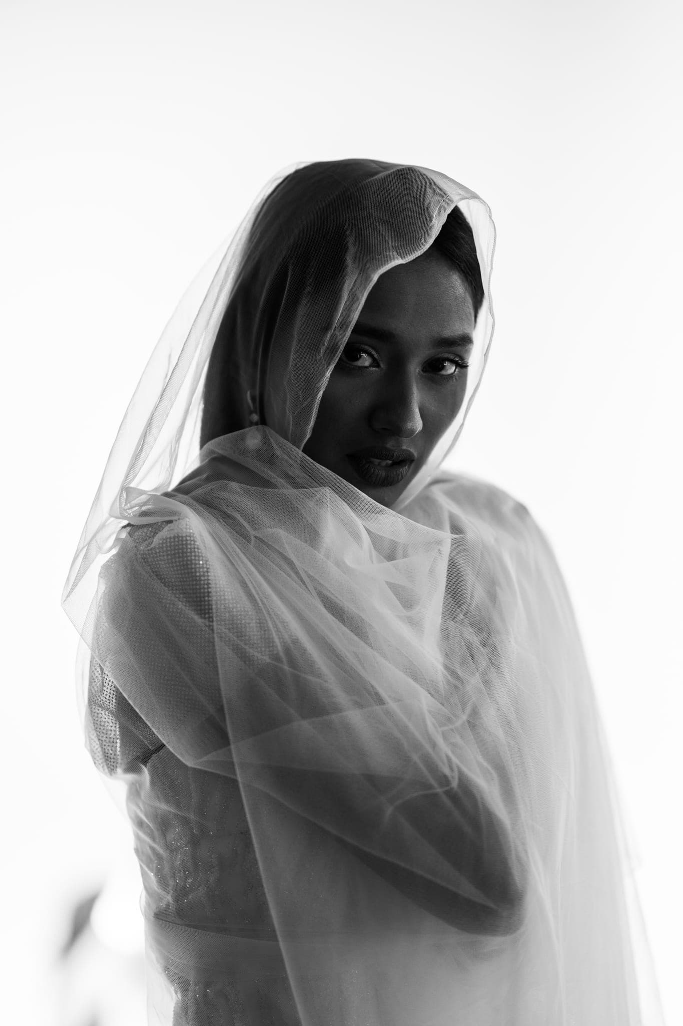 Bride veiled in sheer fabric gazing at camera