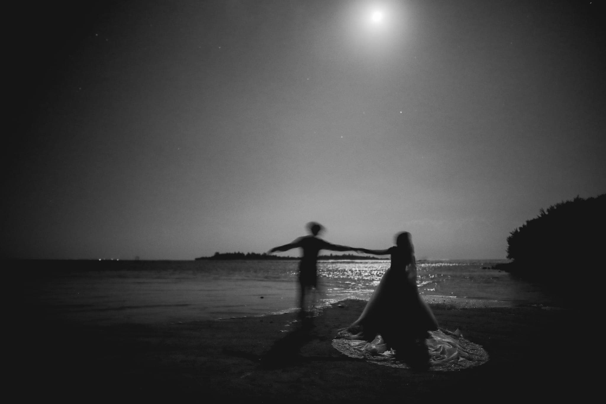 Bride and groom under full moon holding torch flame