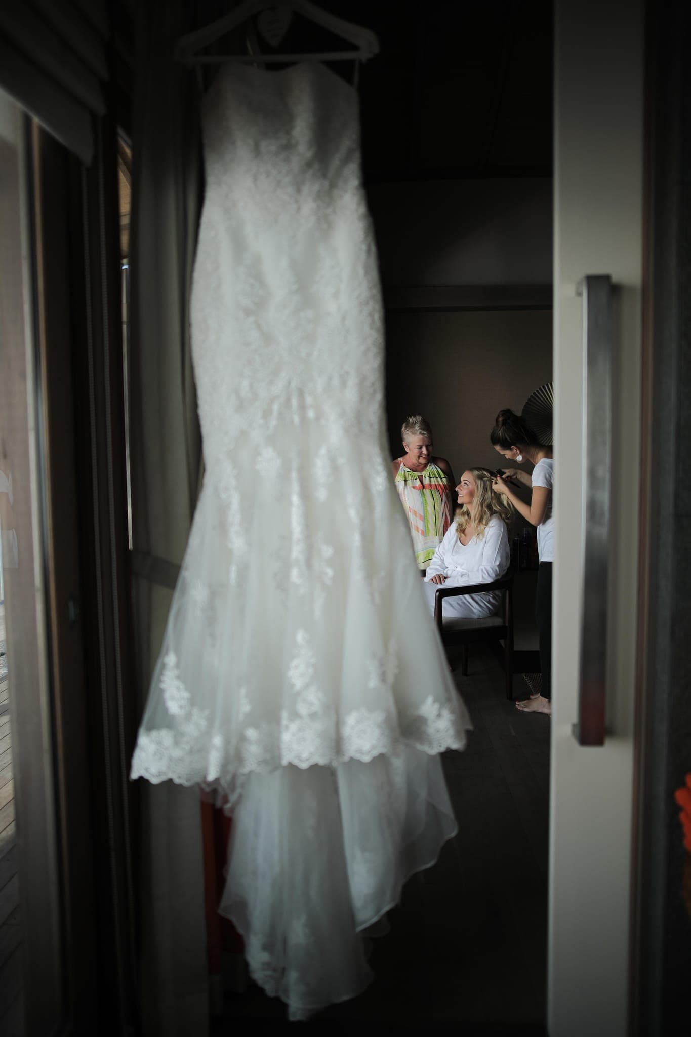 Lace wedding dress hanging by window