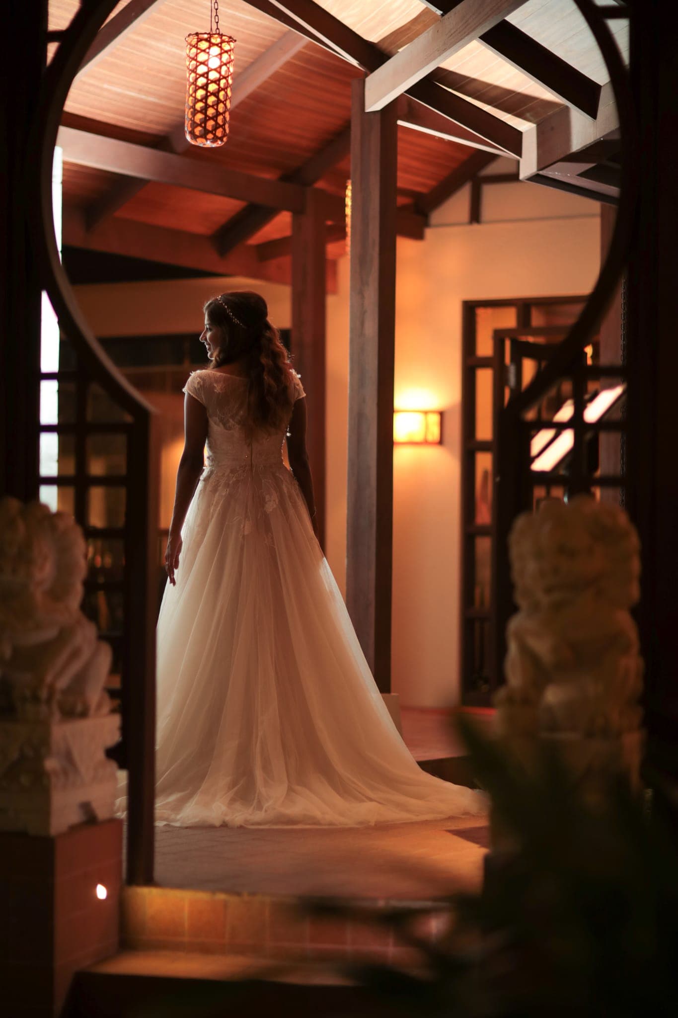 Bride in gown walking through warmly lit circular doorway
