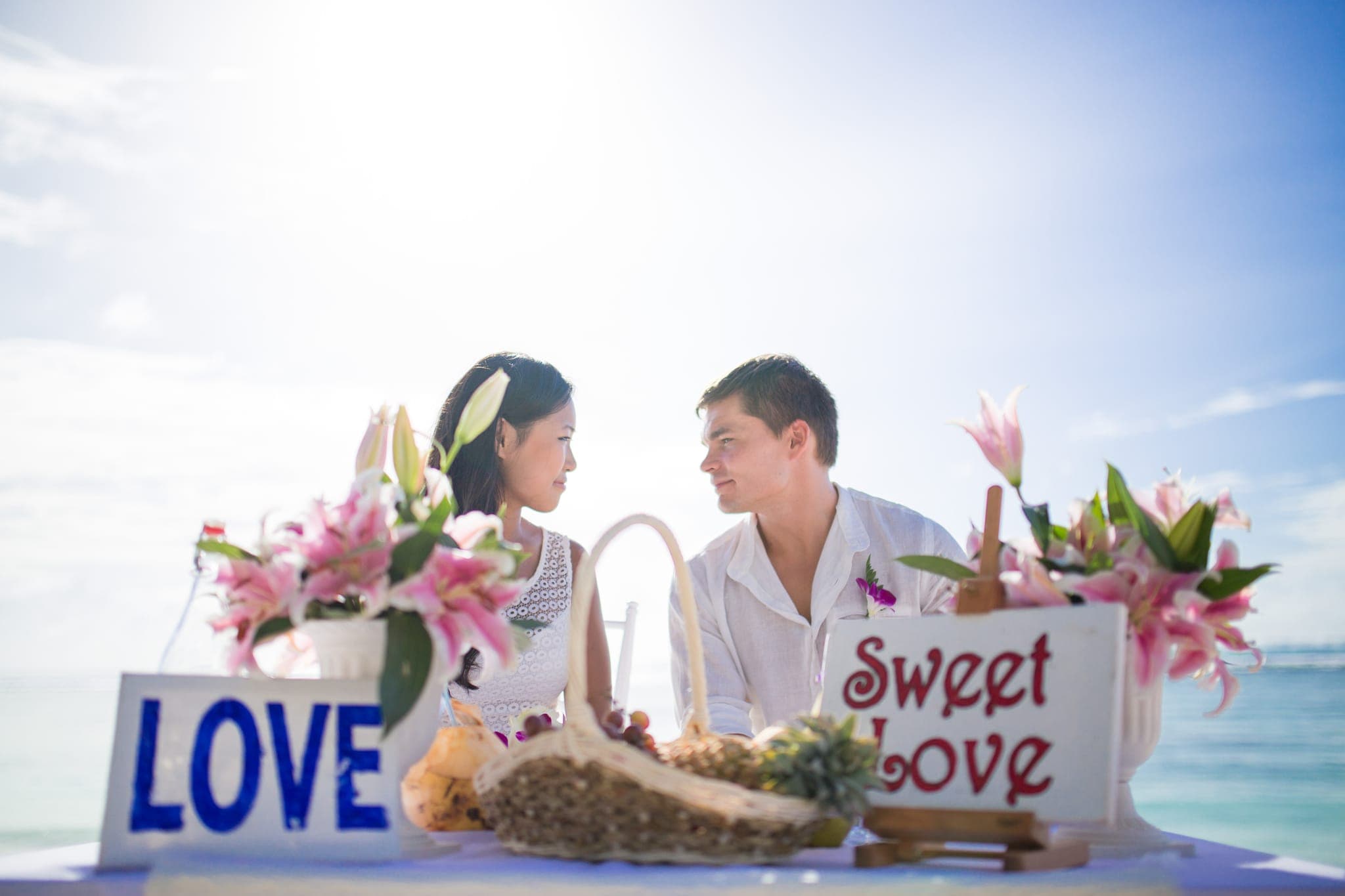 Couple at beach table decorated with love and flower signs