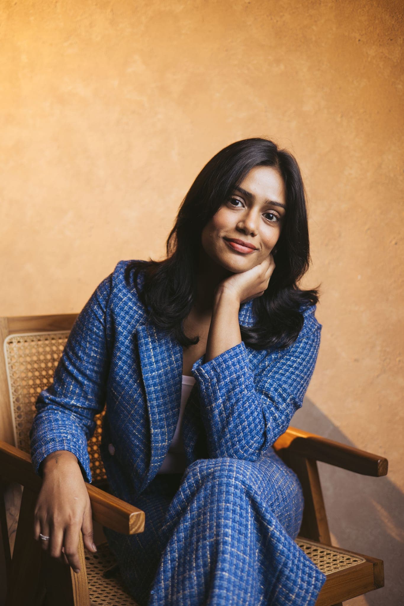 Woman in blue checked dress smiling in wooden chair