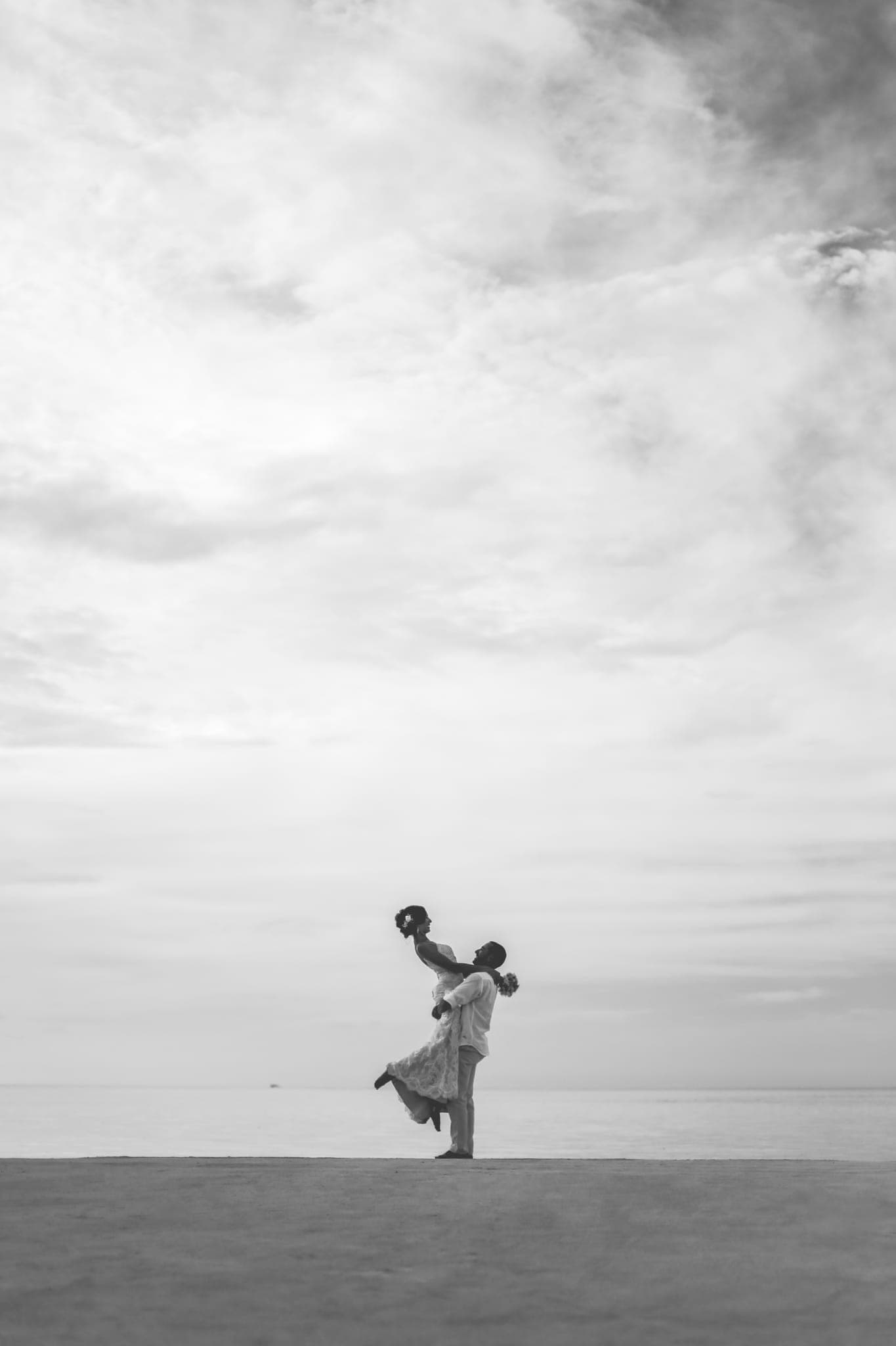 Black and white silhouette of couple dancing on beach
