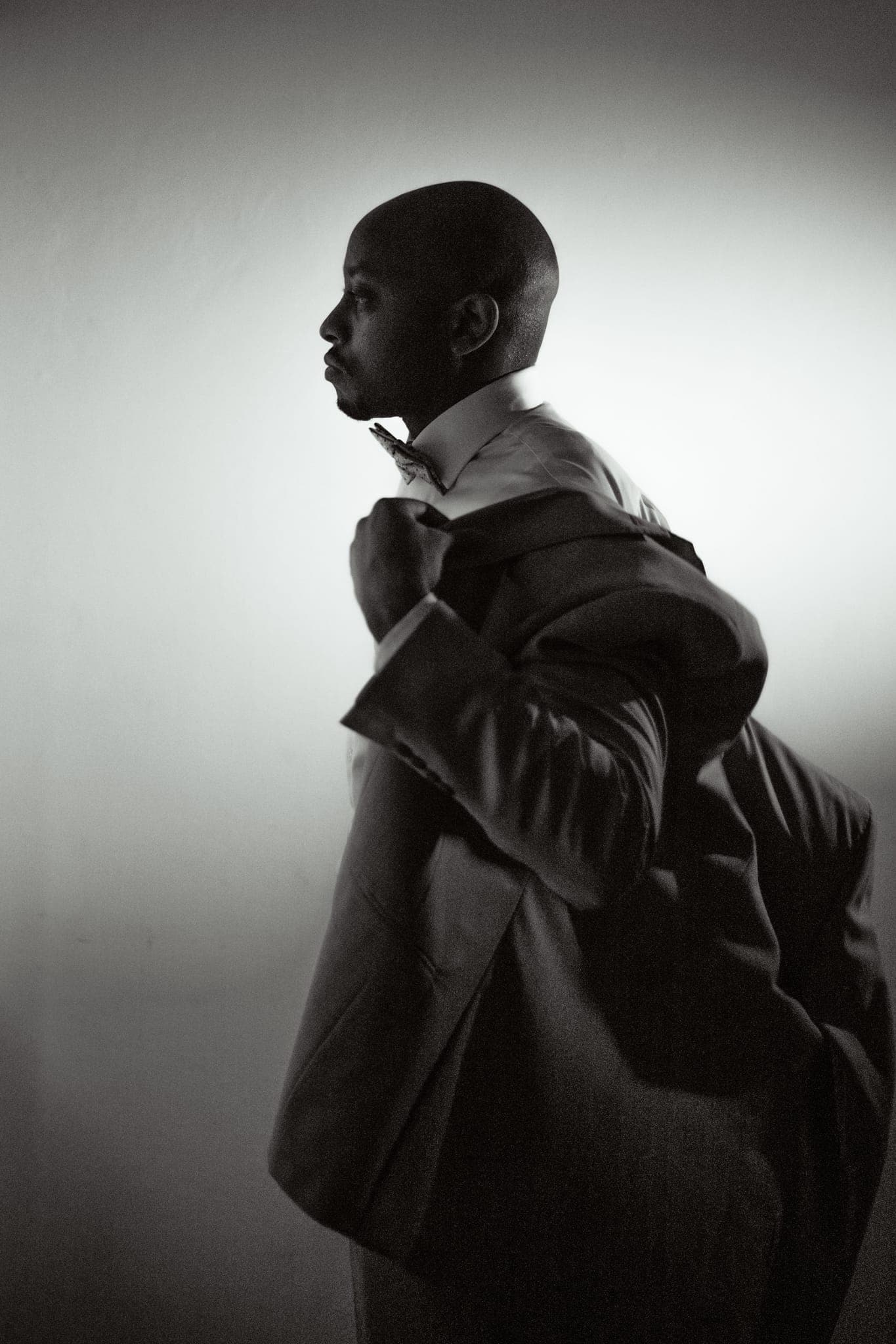Man in suit glancing back, dramatic dark studio light