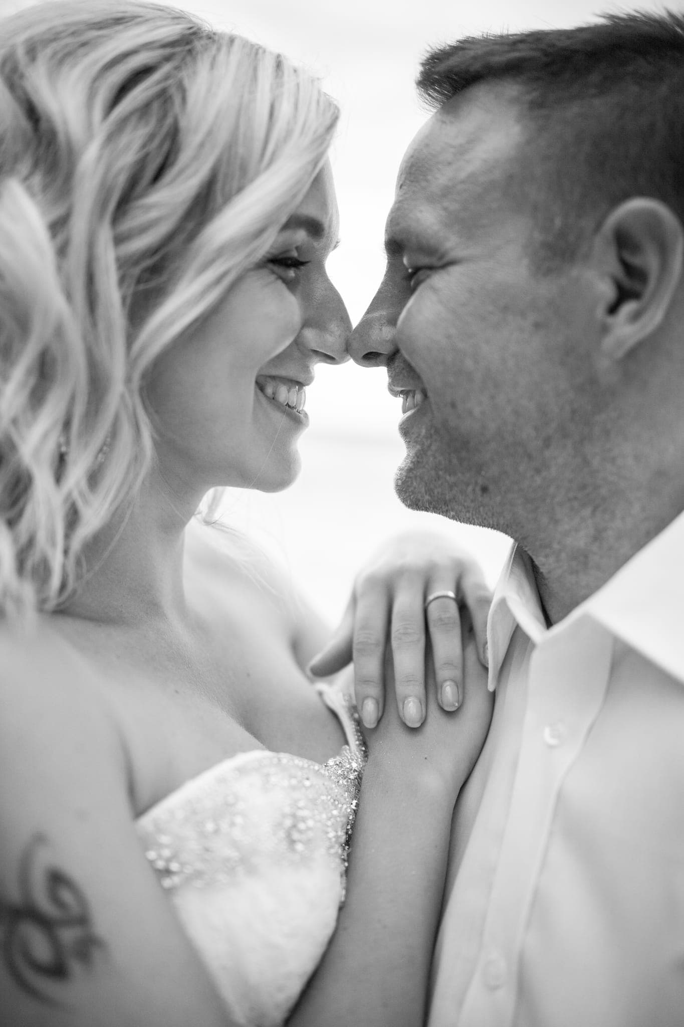 Bride and groom touching noses in close embrace