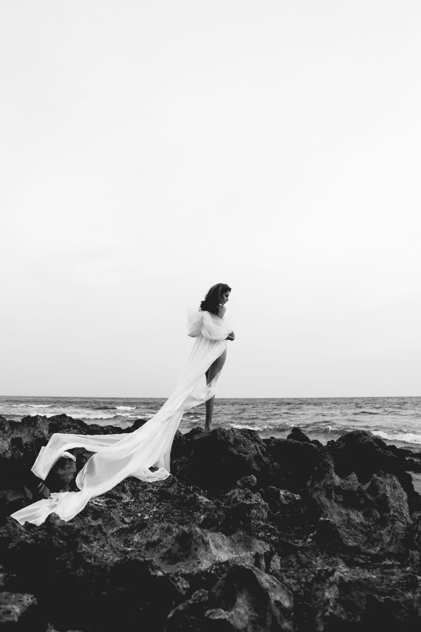 Bride's veil trailing across coastal rocks by sea