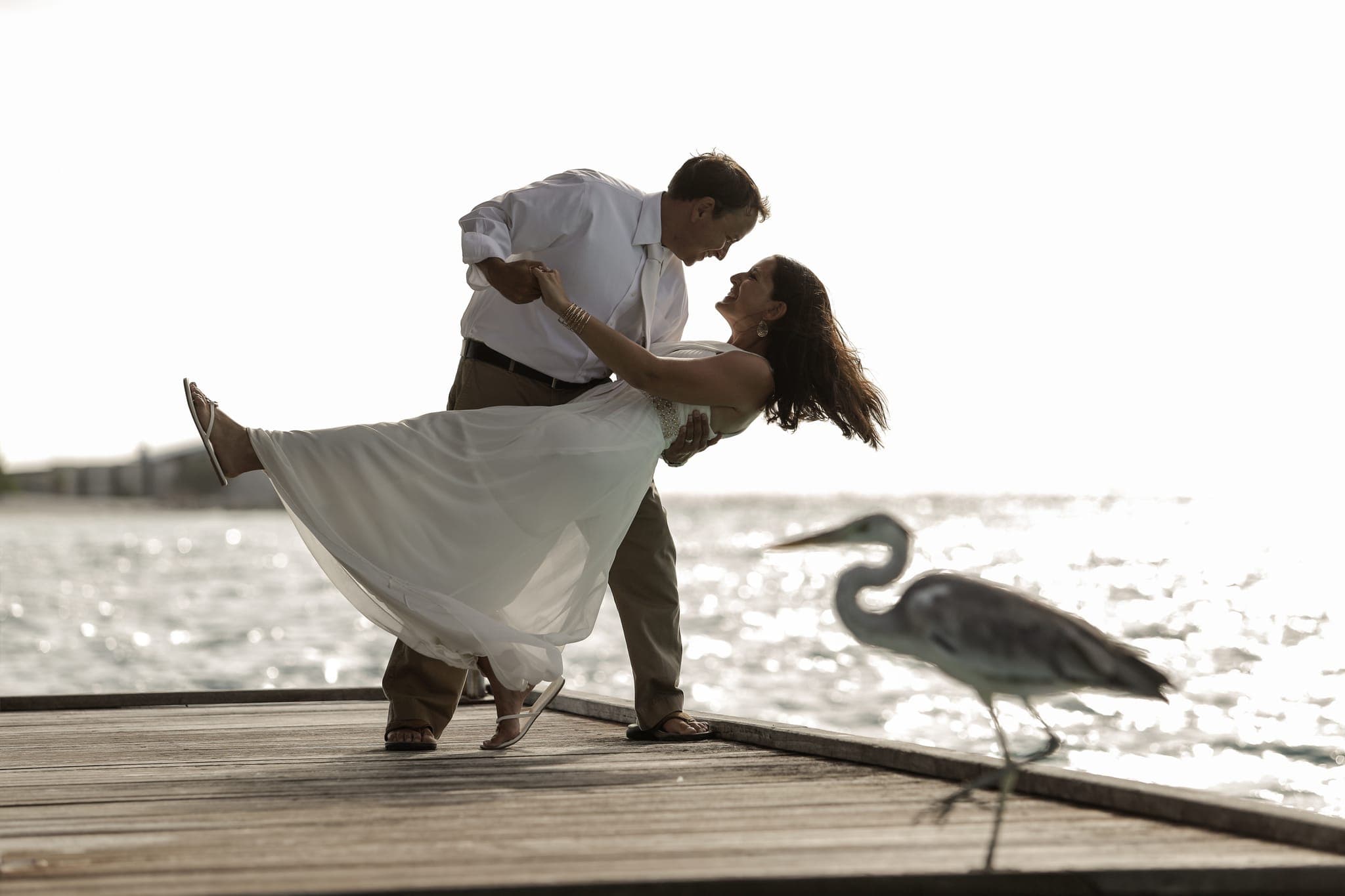 Couple dancing on dock beside a standing heron