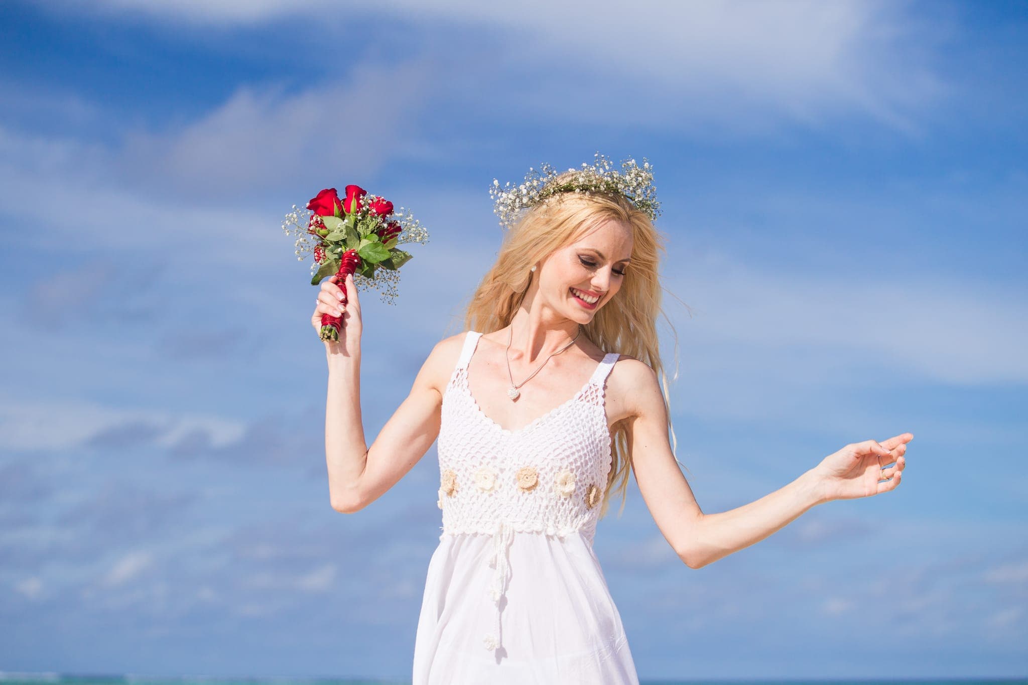 Woman in white dress holding rose bouquet outdoors