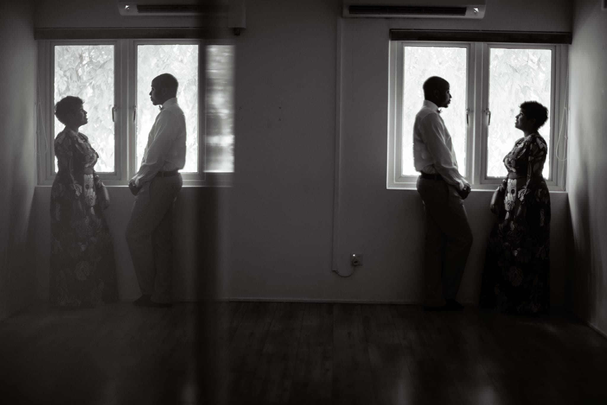 Four silhouetted figures backlit by tall windows