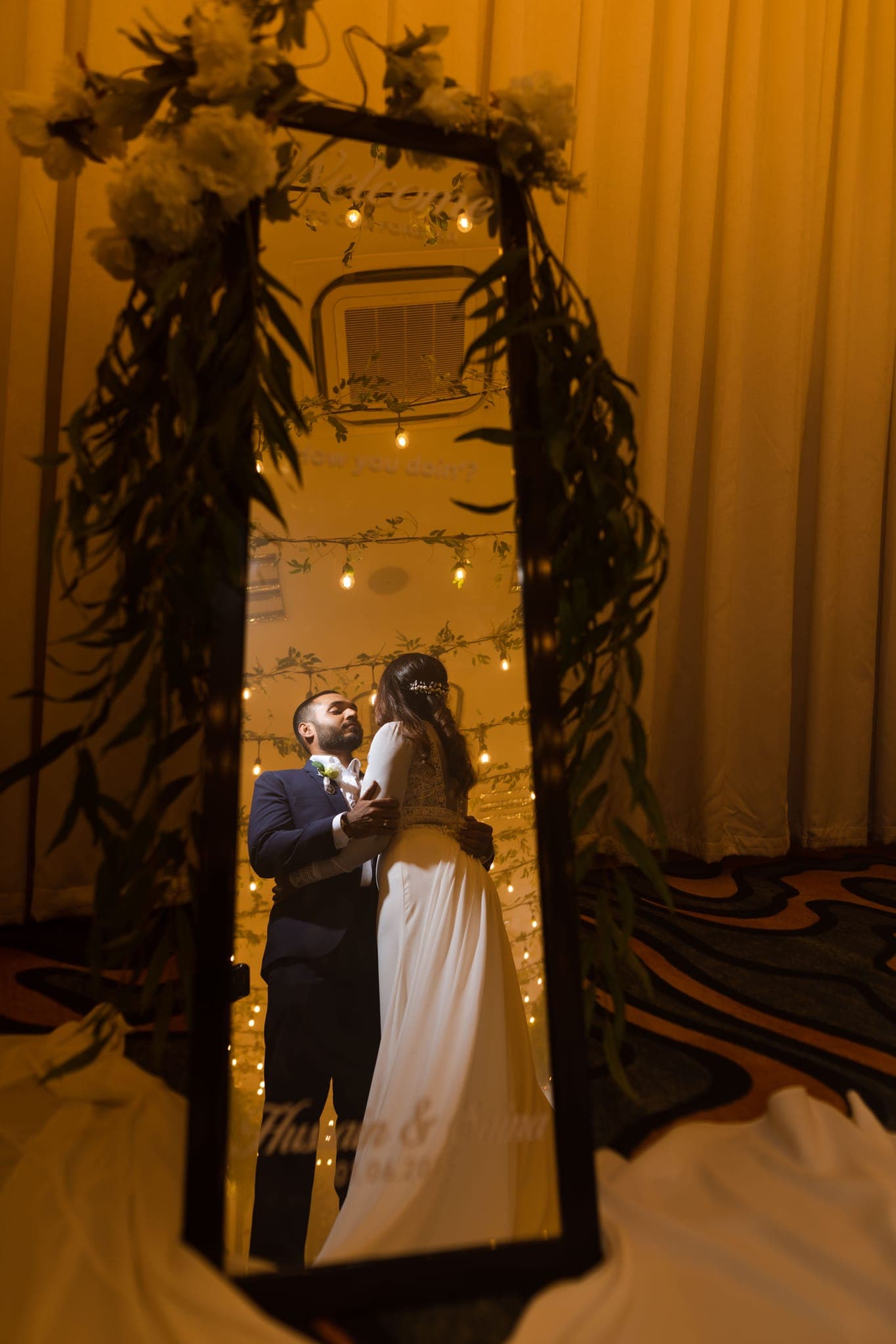 Couple's reflection in mirror framed by fairy lights