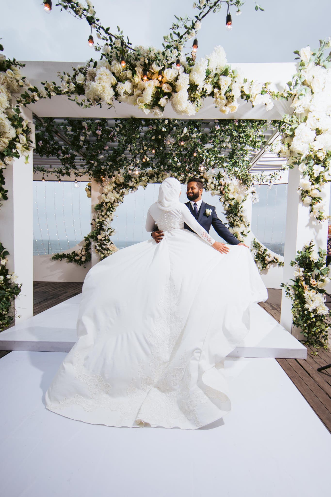 Bride's dress train seen from behind under floral arch