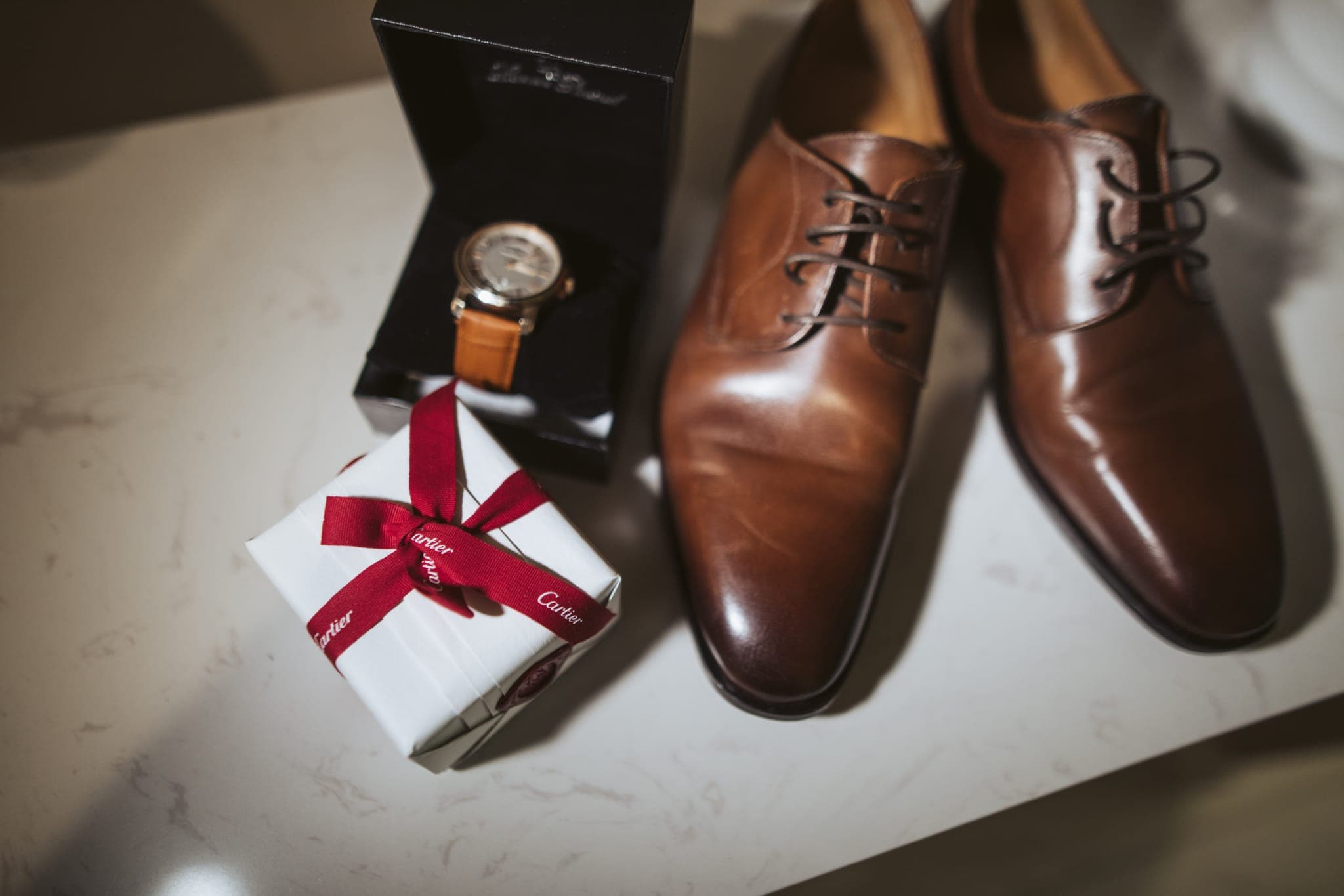 Groom's watch, gift box, and brown leather shoes flatlay