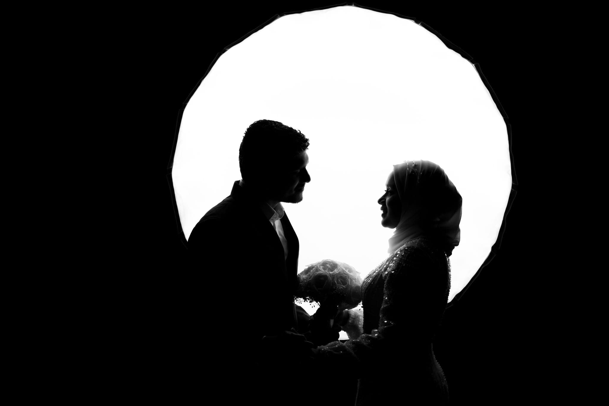Couple silhouetted inside circular archway holding hands