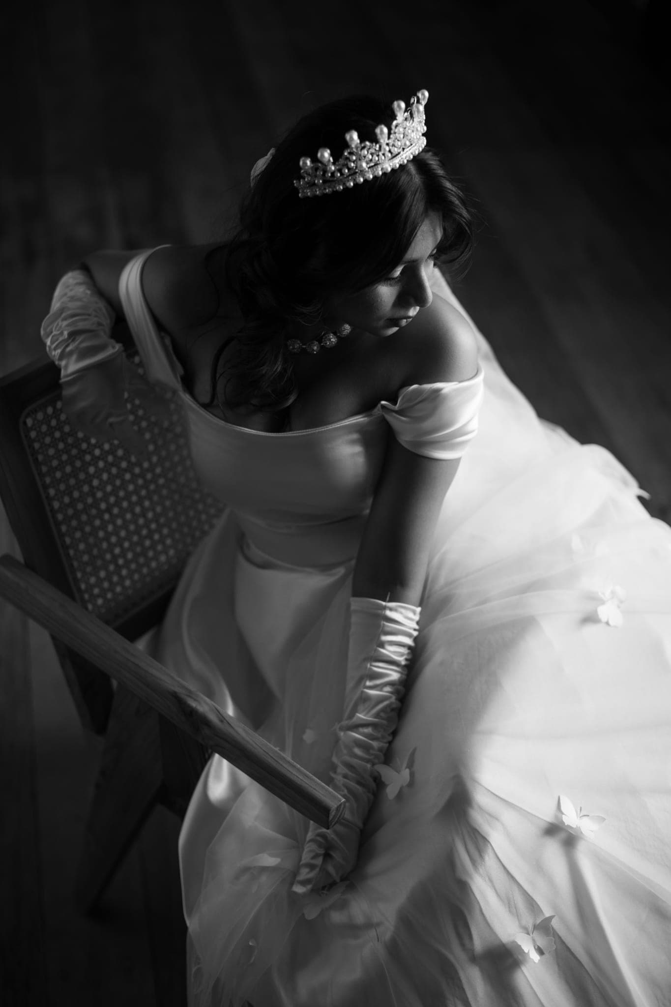 Bride in tiara reclining on chair, black and white