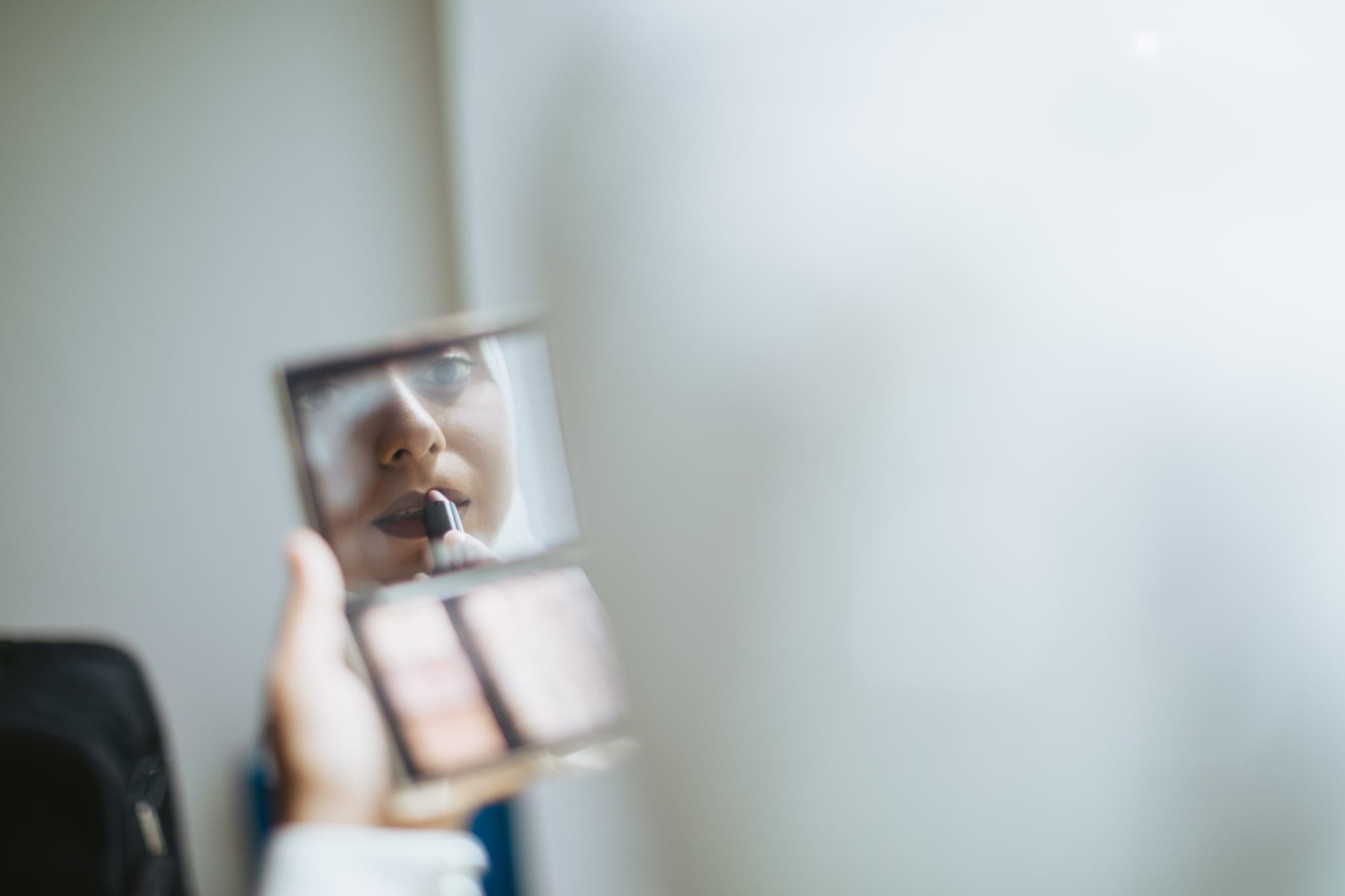 Blurry hand holding makeup compact mirror