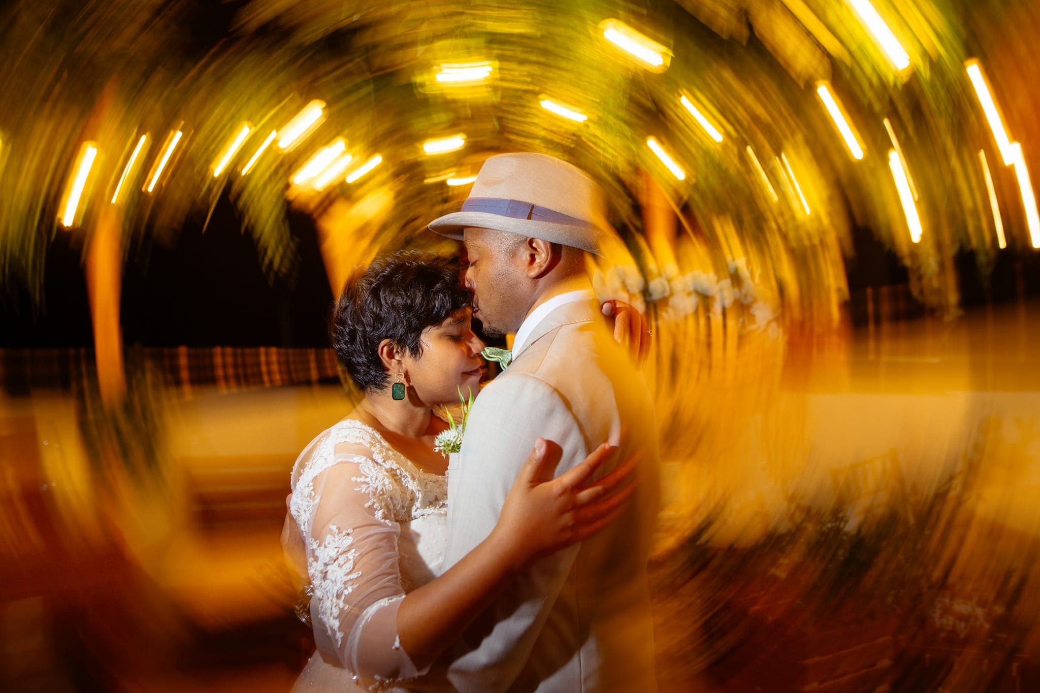 Couple embracing under swirling golden bokeh at night