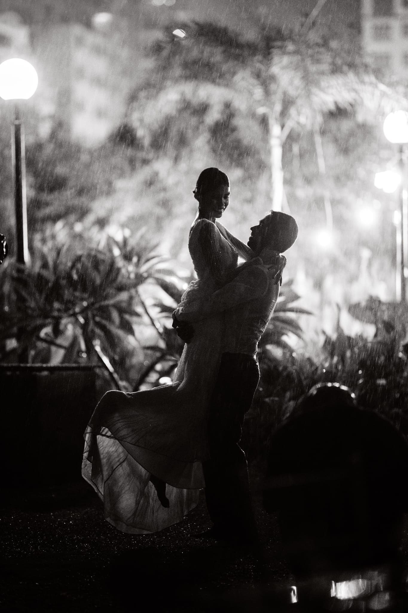 Bride and groom embrace under streetlights at night