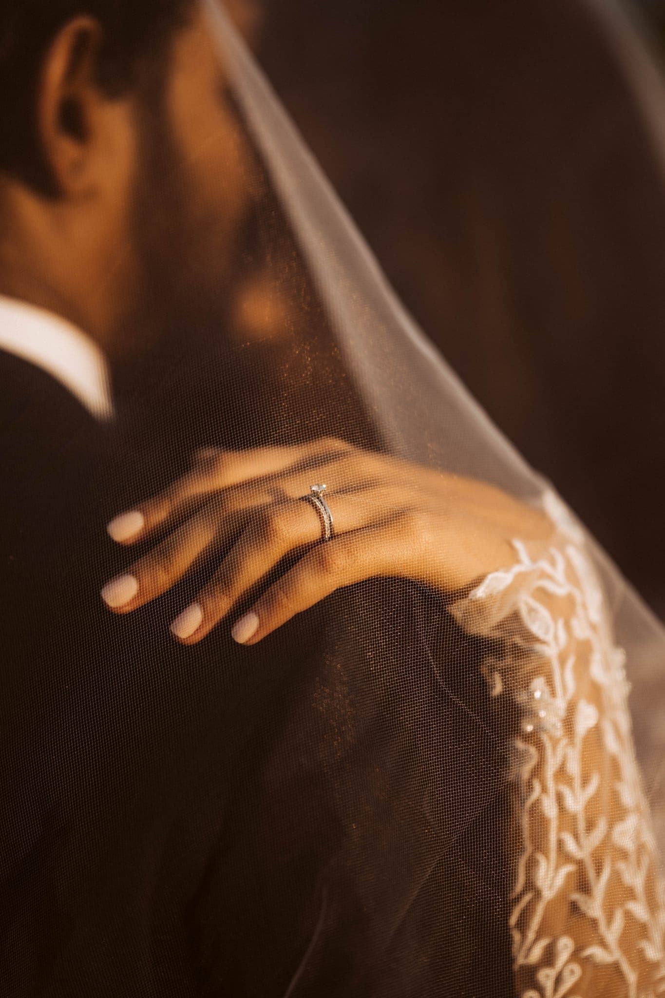 Groom's hand resting on bride's hand under veil