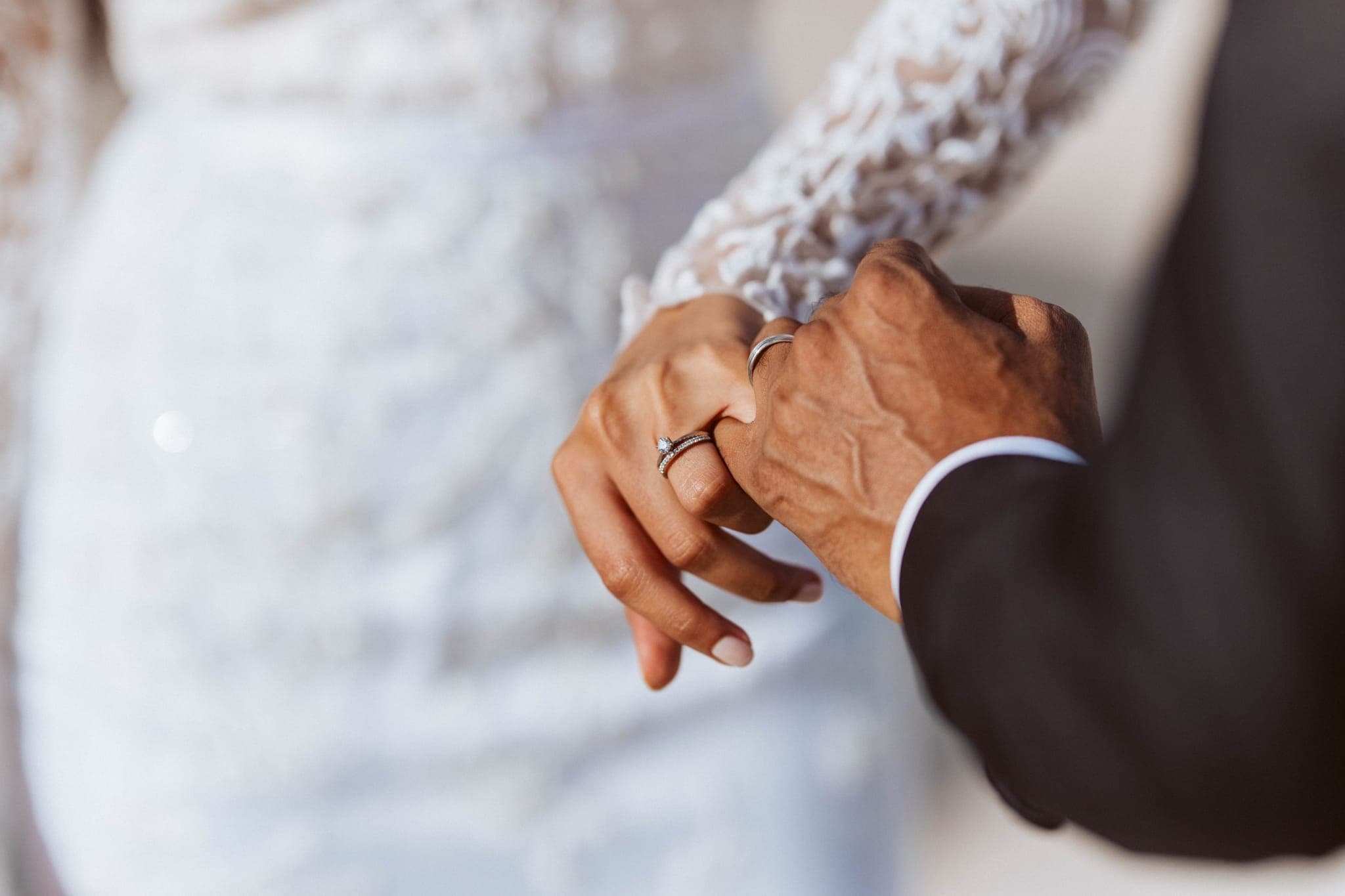 Bride and groom holding hands showing wedding rings