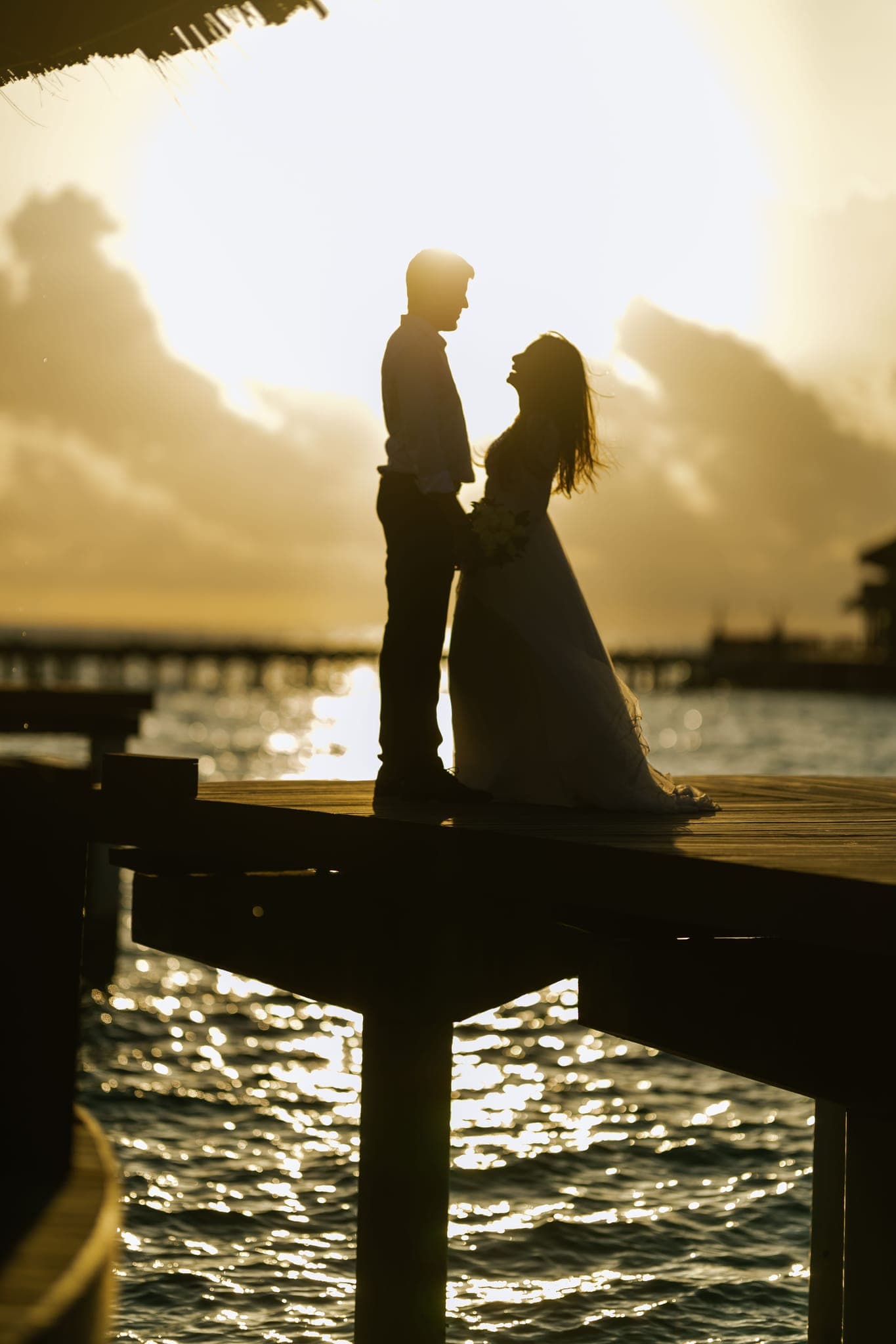 Couple walking along overwater jetty toward tropical island