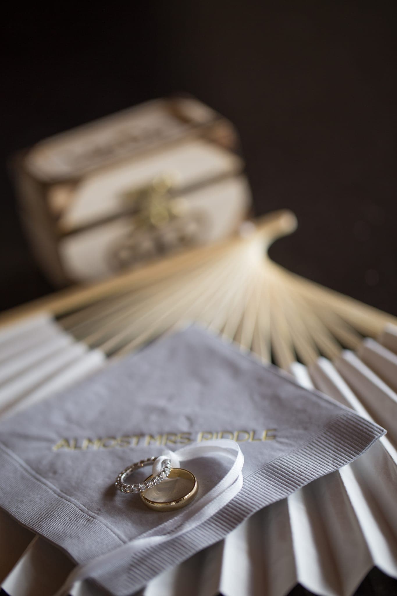 Wedding rings on folded napkin with fan backdrop