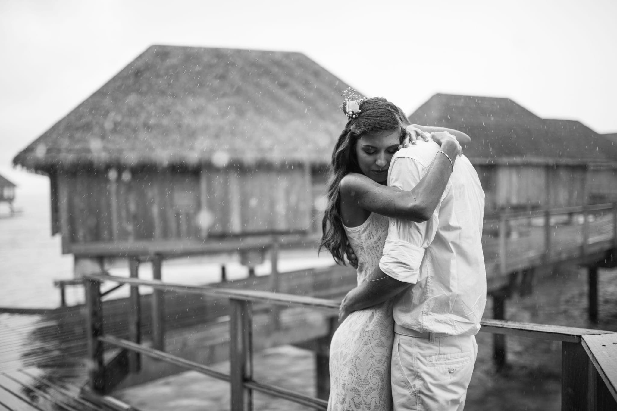Couple embracing on overwater bungalow deck, black and white