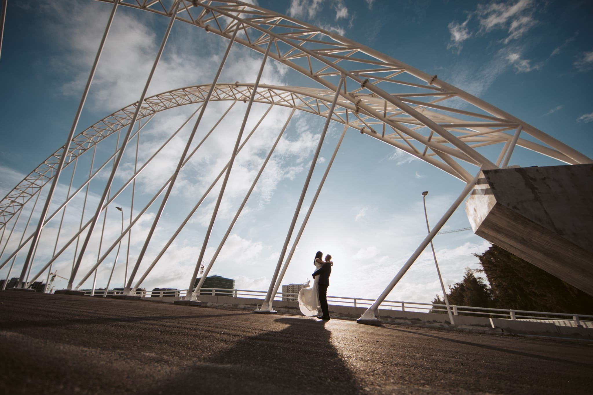 Couple embracing beneath towering steel bridge arch