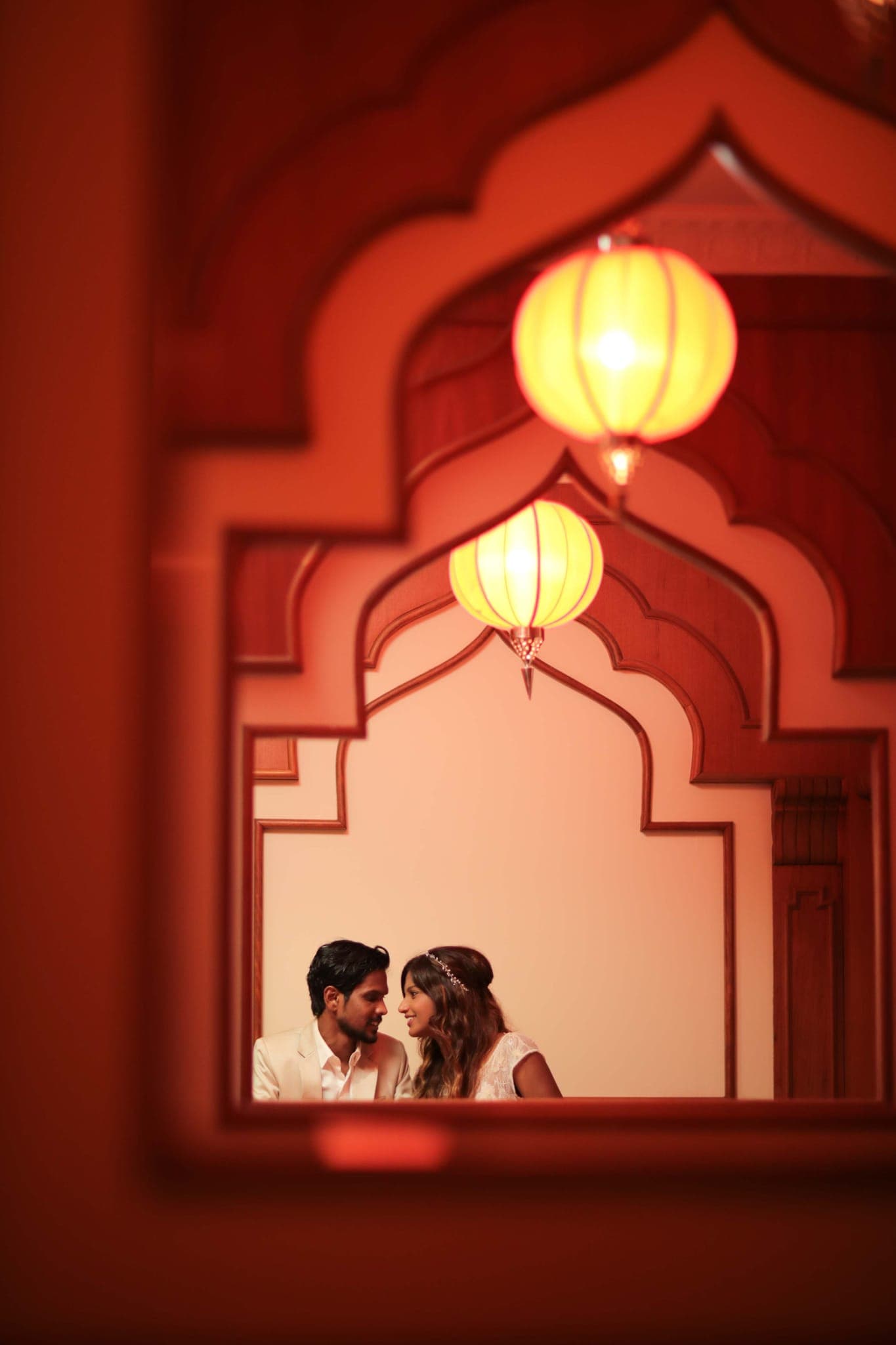 Couple seen through ornate arch with glowing lanterns