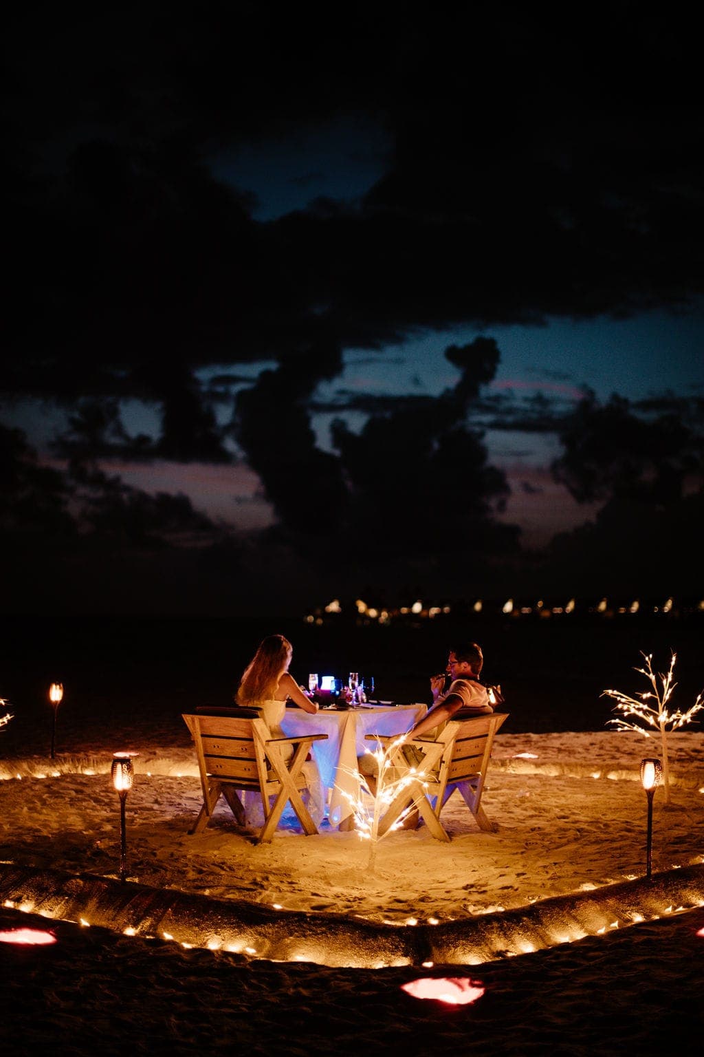 Aerial view of couple at candlelit beach dinner circle