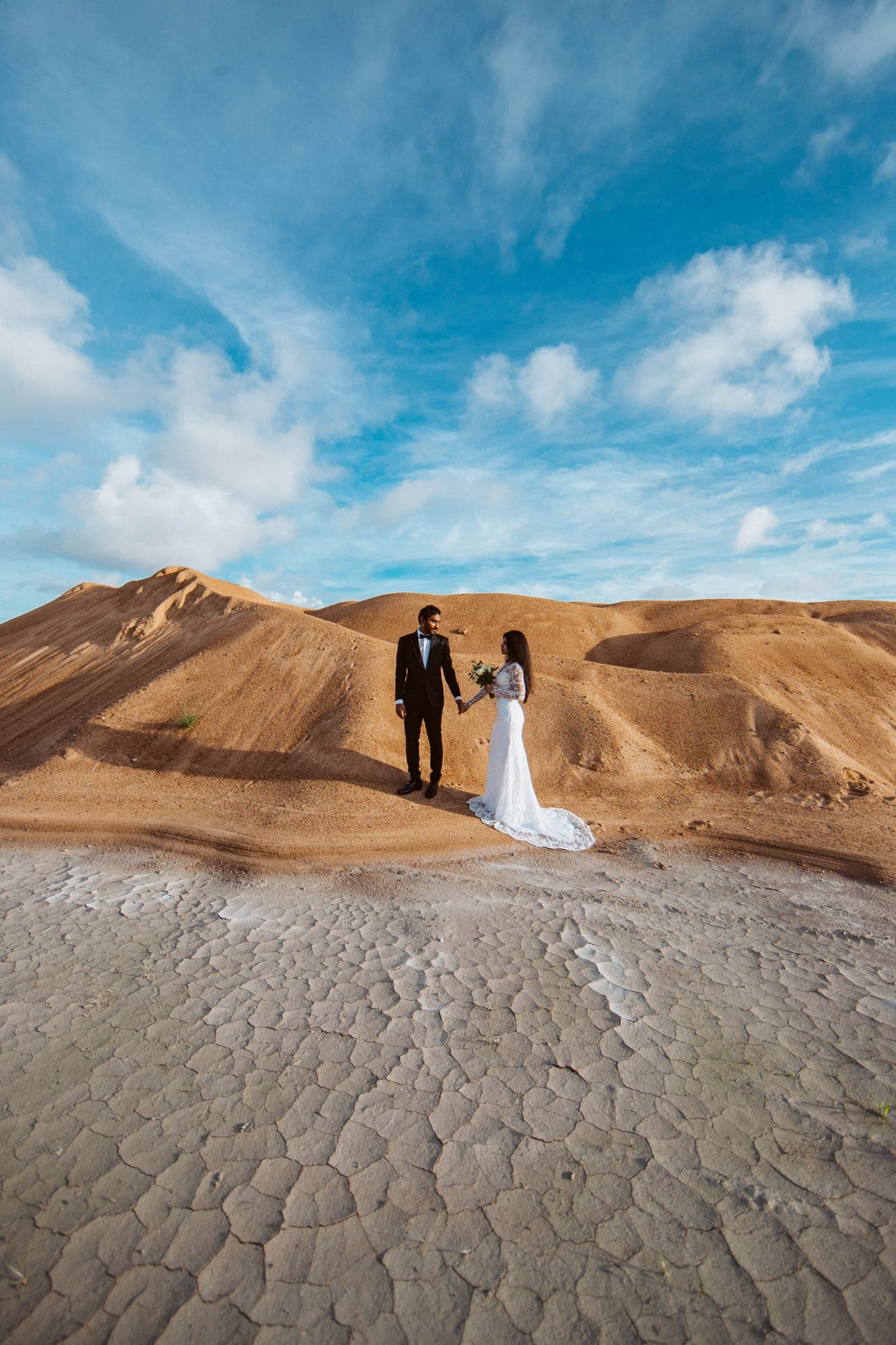 Couple standing on desert sand dunes under blue sky